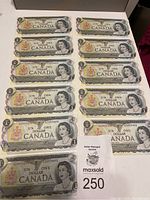 Photo of all 11 uncirculated 1973 Canadian $1 bills laid out in sequence with visible serial numbers and a MaxSold auction card.