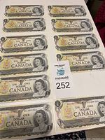 11 Canadian one dollar bills arranged to show front designs, featuring Queen Elizabeth II portrait and Canadian coat of arms.