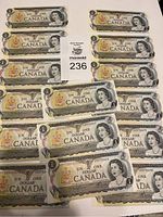 Photo shows all 15 sequential uncirculated Canadian one-dollar bills from 1973 laid out together.