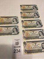 Seven Canadian one dollar bills laid out flat in two columns showing front face with Queen Elizabeth II portrait.