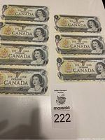 Seven uncirculated Canadian one-dollar bills from 1973 displayed on a white surface, showing two groups, four and three bills respectively.