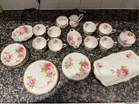 Full display of china set pieces including cups, saucers, plates, and serving trays