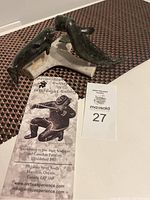 Three dark green stone beluga whales on off-white base, gallery flyer and auction tag visible