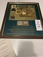 Framed commemorative map with coin and stamp, with seller's auction tag and included letter visible