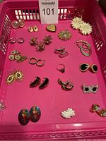 Photo showing 17 sets of assorted earrings including pearl studs, gold-tone hoops, enamel, floral and rhinestone designs.