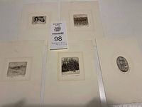 Five miniature etchings displayed on a table showing varied scenes including a rocking chair and landscapes.