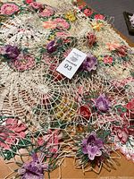 Photo of large round crochet doily with multicolored delicate flowers in various colors including pink, purple, yellow