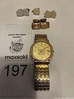 Overview showing gold-tone Birks wristwatch and four pairs of vintage men's cufflinks/buttons on white surface with auction card.