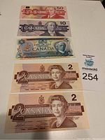 Five older Canadian banknotes displayed with $50, $10, $5 and two $2 bills including uncirculated $2 bills