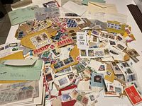 Image showing a large assortment of loose postmarked stamps, many attached to torn paper and envelopes, spread on a surface.