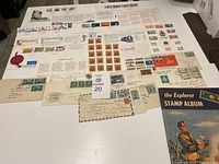 Photo showing an assortment of Canadian stamped envelopes, a sheet of stamps and various postage marks spread out on a table.