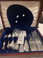 Wooden chest lined in blue velvet showing packed knives, forks and spoons in plastic sleeves