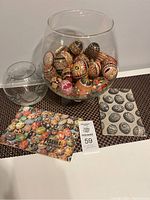 Photo of 38 decorated Ukrainian Easter eggs displayed inside a large clear glass bowl with the smaller glass bowl beside it along with two booklets about pysanka eggs.