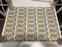 Top-down view of 40 one-dollar bills arranged in eight columns by five rows on table with jars at corners