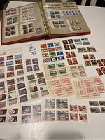 Overview of the collection showing a spiral-bound album open to pages with multiple Canadian stamps and several sheets of loose stamps on the table.