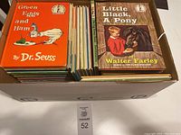 Box of vintage children's books showing Green Eggs and Ham by Dr. Seuss and Little Black, A Pony by Walter Farley on top
