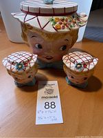 Cookie jar and matching salt and pepper shakers displayed together on table with auction tag.