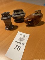 Three vintage lighters together on table showing different distinct styles including two Ronson and one Japanese lighter.