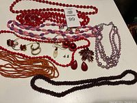 Overview of all jewelry items including necklaces, brooch and earrings laid out on white surface