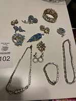Overview of the set showing 2 necklaces, 2 bracelets, 5 brooches, and 4 sets of earrings all laid out on a table.
