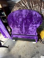 Purple upholstered twin bed footboard with button tufting, showing fabric texture and scratches.