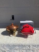Photo showing both the copper and brass chafing dish and the boxed red porcelain baker with warmer stand together.