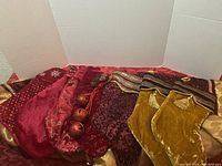 Seven red, gold, and burgundy Christmas stockings displayed together, showing different designs and decorative details including tassels and patterned fabric.