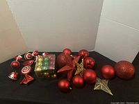 Side view of the lot showing grouped red and gold/glitter ornaments, stars, candy-shaped, and a box of multi-colored mini balls