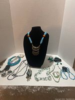 Full view of all item sets including necklaces, earrings, and bracelet on a display stand and flat surface