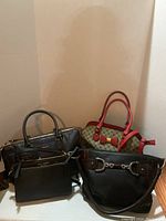 Four handbags grouped together against wall, displaying size and general appearance