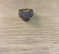 Top view of 10k gold engagement ring with cluster of stones on wooden surface