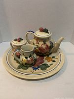 Photo shows teapot with lid, sugar bowl with lid, creamer, and large round platter with hand-painted floral Orleans pattern.