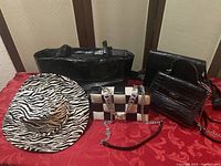 Four handbags and one hat arranged on a red surface. Items show significant signs of use and some wear.