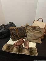 Five handbags and a sleeveless sweater top with faux fur trim displayed together. Various styles and colors including leopard print, beige, black, and tan.