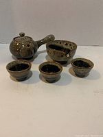 Korean style porcelain tea set including teapot, pitcher bowl, and three tea cups displayed on white surface.