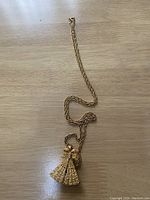 Full view of the gold chain and closed mechanical fan pendant with embedded stones.