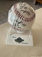 Side view of the signed 1992 Blue Jays World Series baseball in clear plastic case on pedestal label.