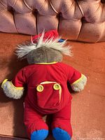 Back view of Bedtime Bubba Bear plush showing flap with two yellow buttons on red pajamas.