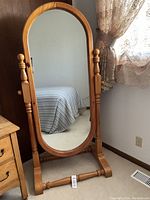 Front view of the full length oval mirror on pine stand showing the turned spindle side supports and honey pine finish.
