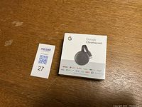 Front of sealed Google Chromecast box showing product image and streaming service logos.
