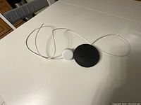 Black and orange Google Nest Mini smart speakers on a white table with a white power adapter and cable.