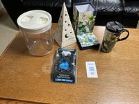 Photo showing all items: clear storage container with white lid, ceramic candle holder, travel mug in box, ice grippers in packaging.