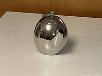 Close-up view of teapot lid with knob in closed position showing smooth reflective surface