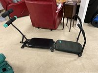 Side view of ab exerciser showing padded black seat and green padded backrest with green 2 lb weights attached on handles and black foam grips.