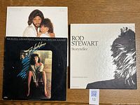 Rod Stewart Storyteller CD box and Flashdance soundtrack album side by side on wood surface