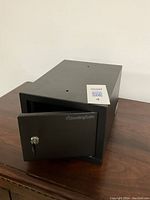 Closed view of small black SentrySafe with key inserted in lock on front door.