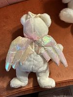 Back view of large white bear showing iridescent angel wings and white fur.