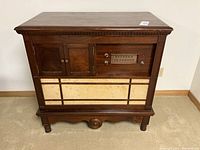 Front view of vintage wooden cabinet with radio tuner and speaker panel visible.