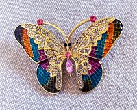 Front view of the colorful butterfly brooch exhibiting multicolor enamels and clear plus pink rhinestones on gold-tone metal.