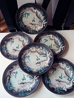 Five handmade decorative plates arranged to show the dragon design on each, displaying the set and overall theme.